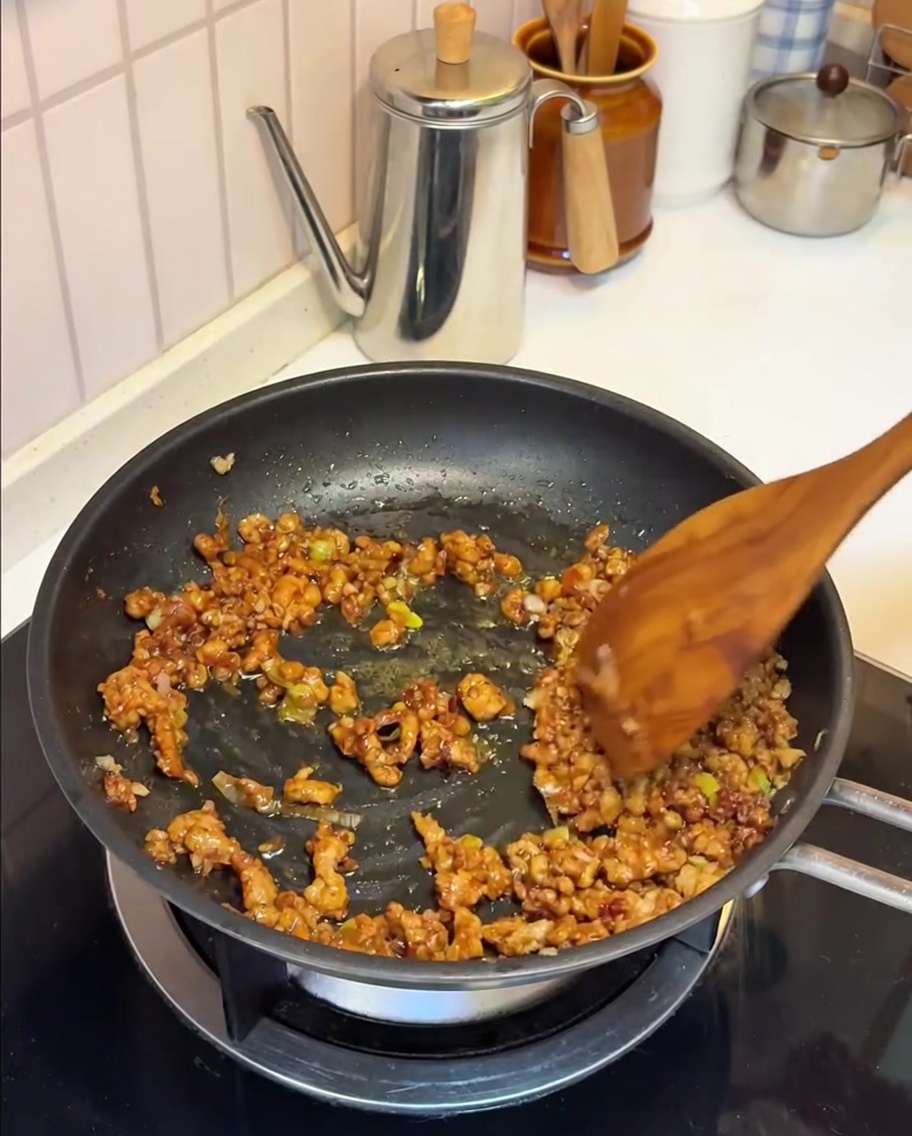 Soy milk being poured into the pan with the savory pork and miso mixture.