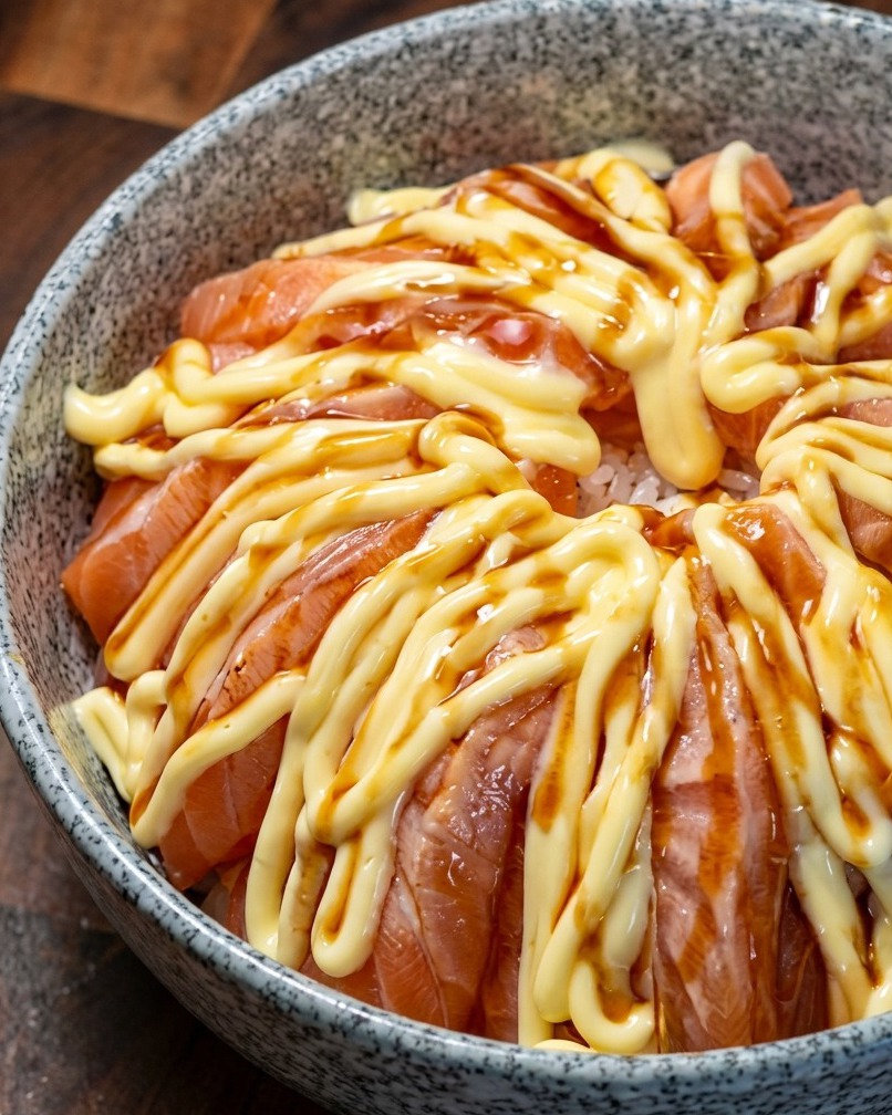 A salmon rice bowl drizzled with dark teriyaki sauce over the layer of mayonnaise.