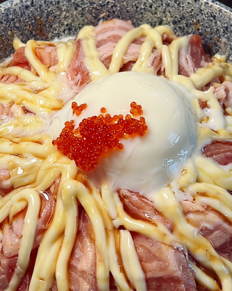 Close-up of a salmon rice bowl topped with a runny egg and bright red fish roe.
