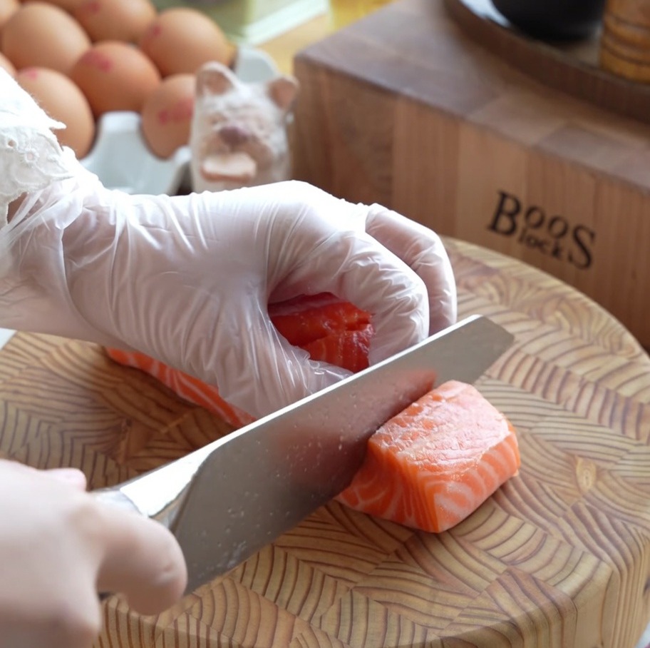 Thick cubes of raw fresh salmon neatly prepared on a wooden cutting board.