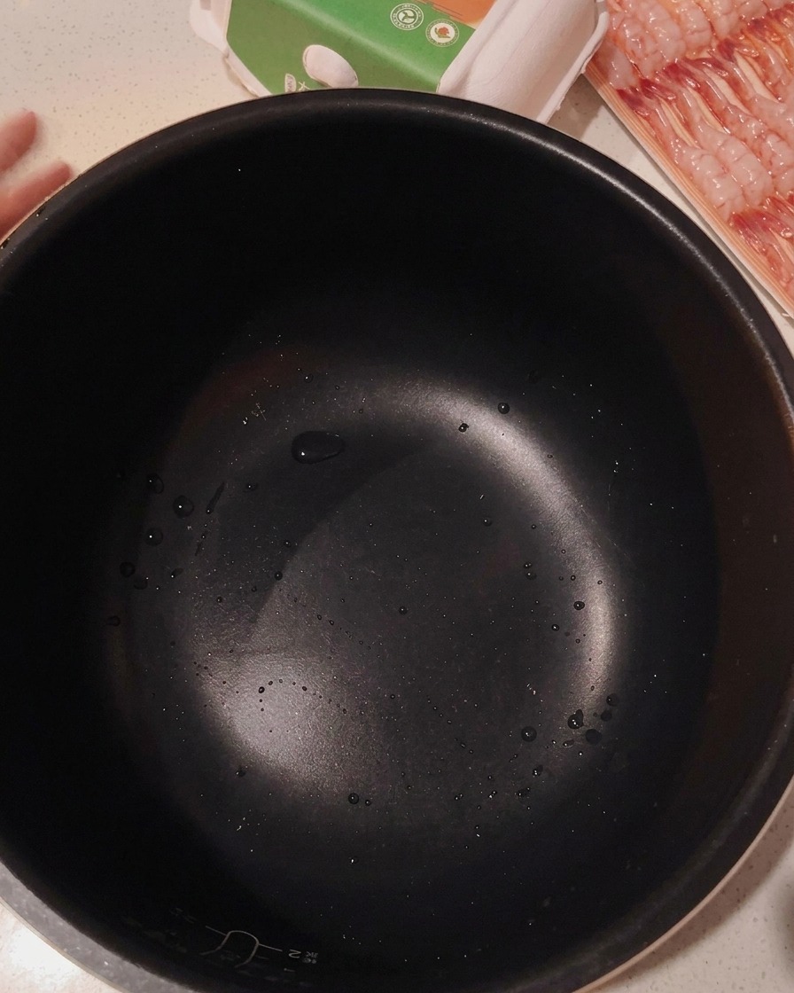 Uncooked white rice in a black rice cooker pot, ready to be washed.