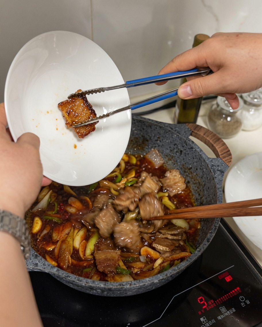 Pork belly slices being added from a plate into a wok filled with sizzling sauce and vegetables.
