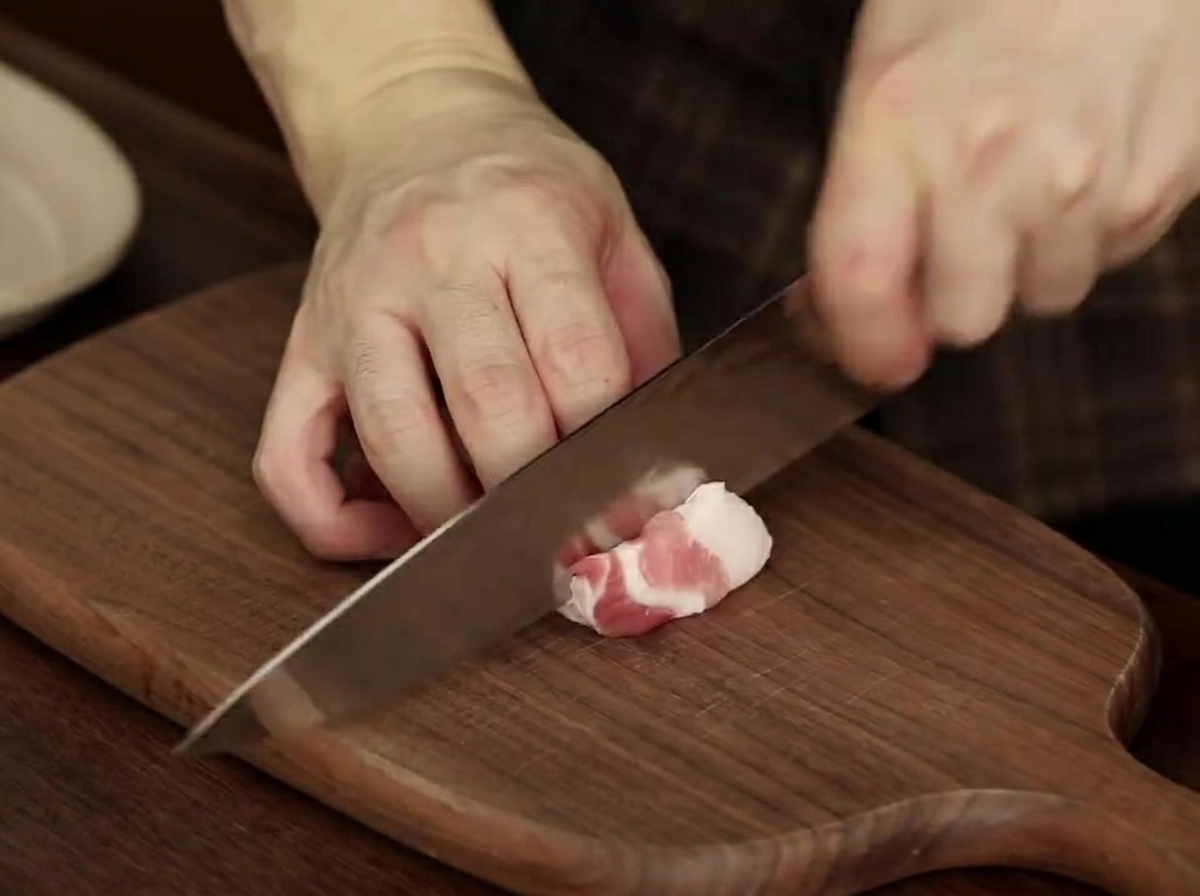 Slices of raw pork belly arranged neatly on a plate, prepared for the stew.