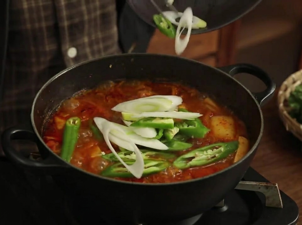 Sliced green peppers and leeks being added to the bubbling stew.