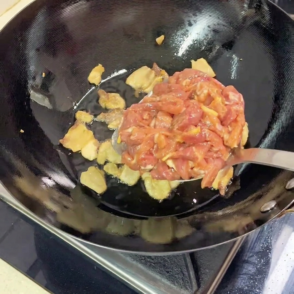 Marinated lean pork strips being added to the hot wok with the rendered pork belly.