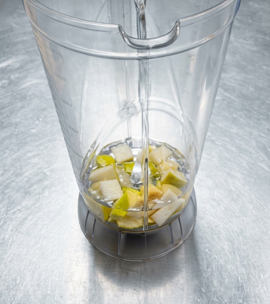 Chopped aromatics in a blender being topped off with water before blending.