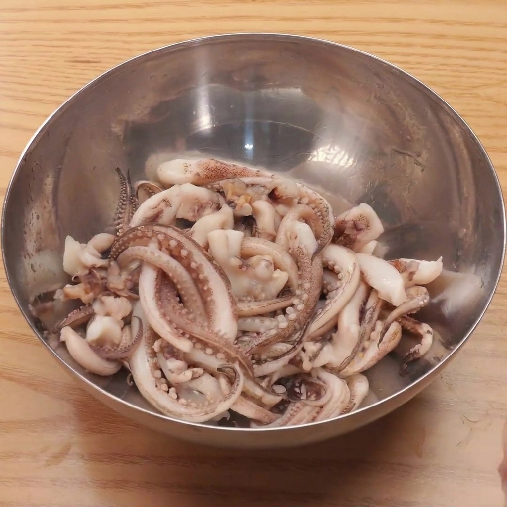 Fresh squid legs submerged in a bowl of boiling water for a quick blanch.