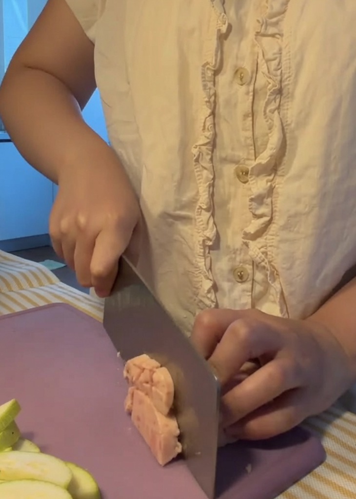 Luncheon meat being cut into small, even cubes on a purple cutting board.