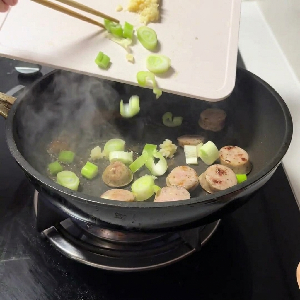 Fresh chopped green onions and minced garlic being dropped into the pan with the meat.