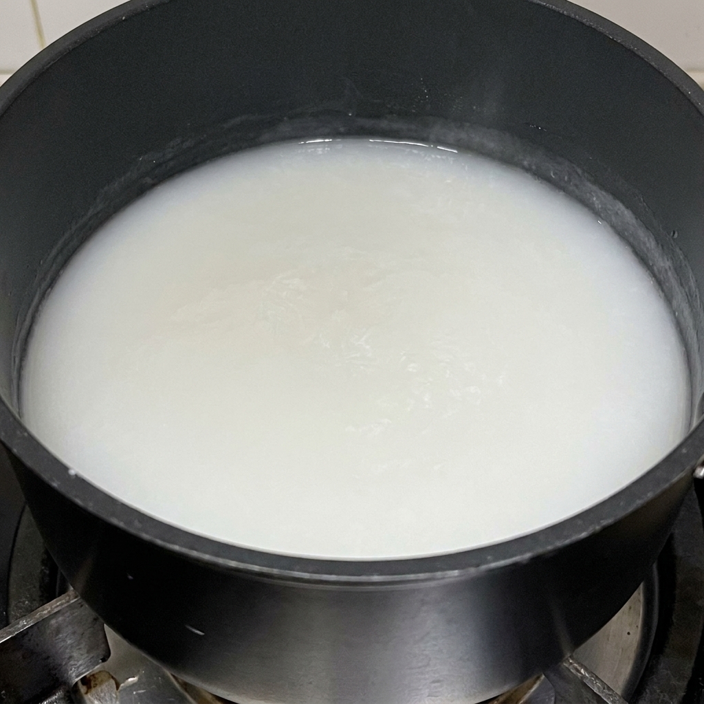 A thick, white glutinous rice flour paste cooking in a black pot.