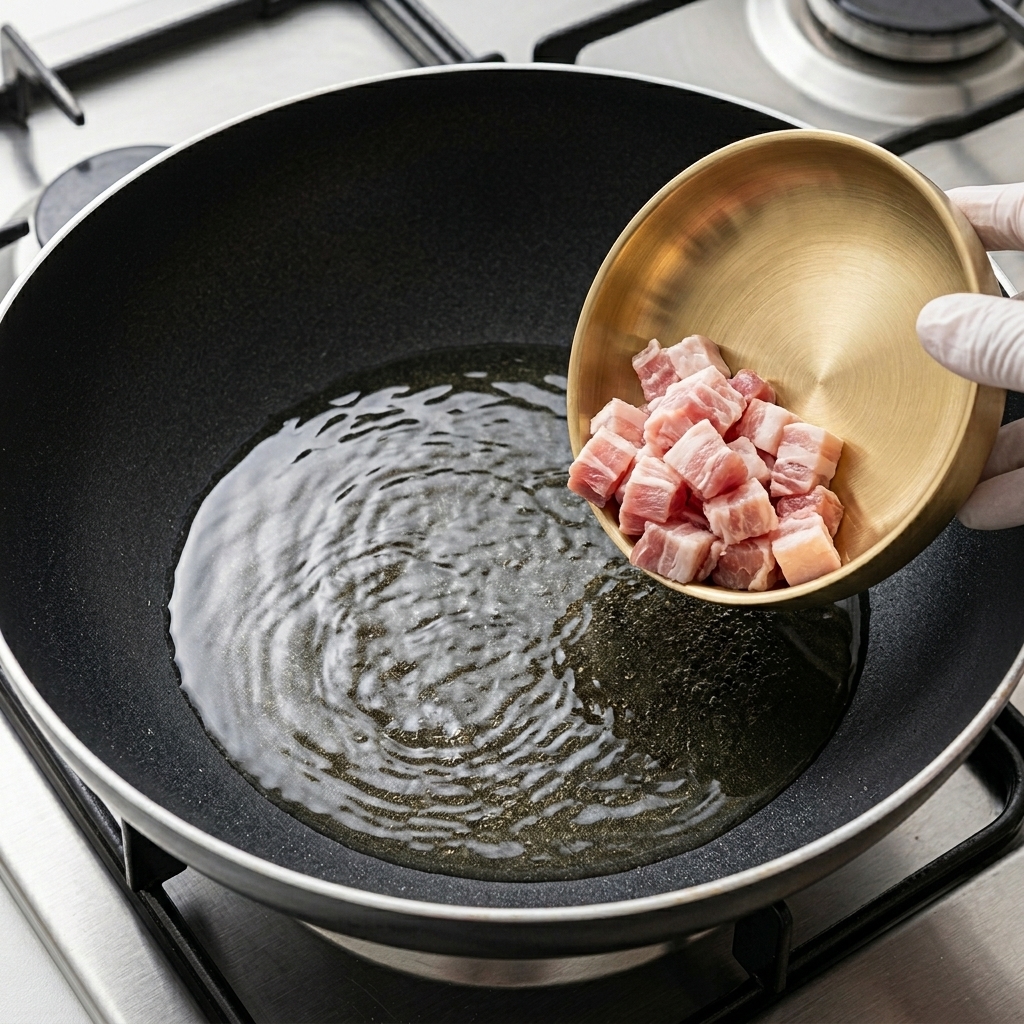 Thin slices of pork belly browning in a hot pan.