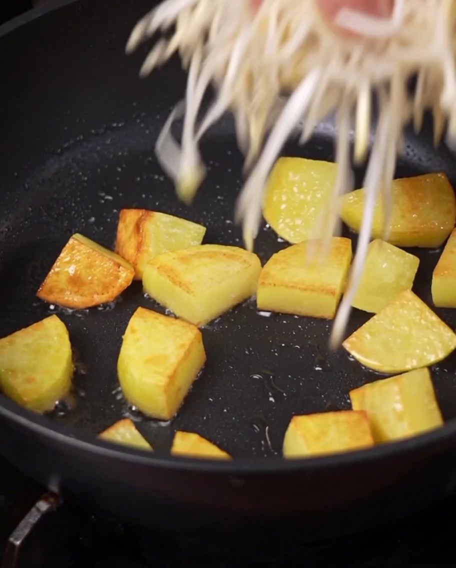 Fresh bean sprouts and a cluster of enoki mushrooms being placed into the pot.