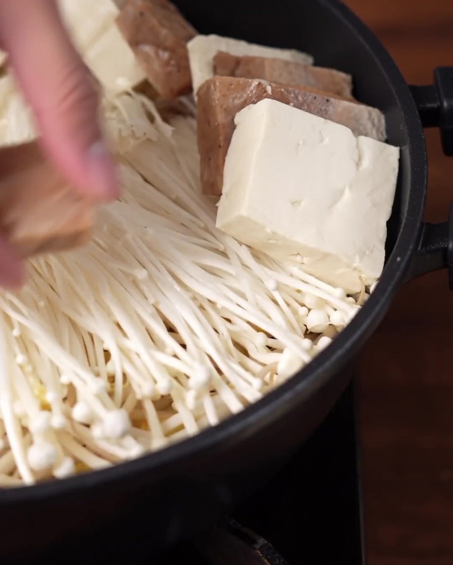 Slices of tofu and vegan luncheon meat arranged in a circular pattern inside the pot.