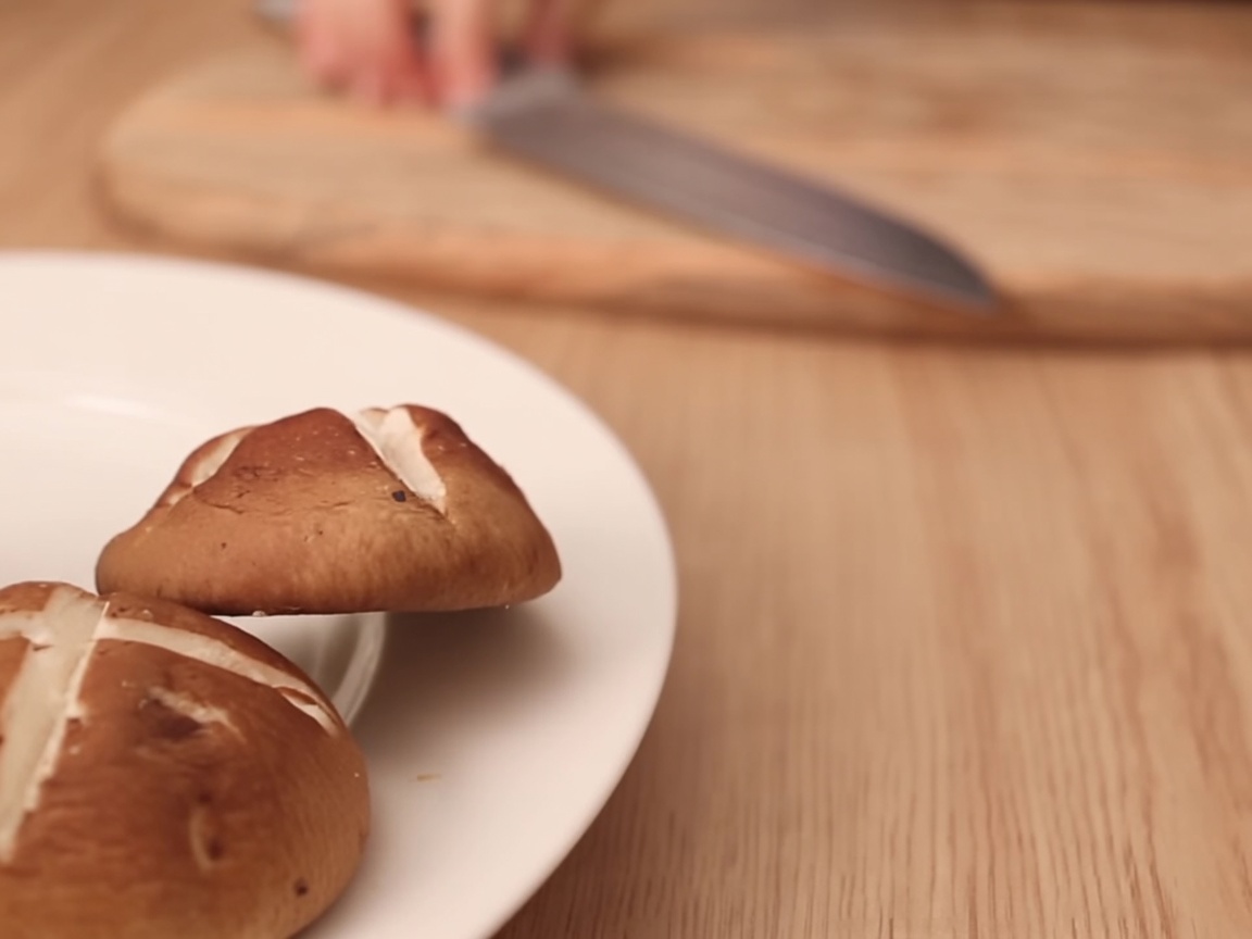 Vegetarian sweet fish cake being sliced into strips on a wooden cutting board.