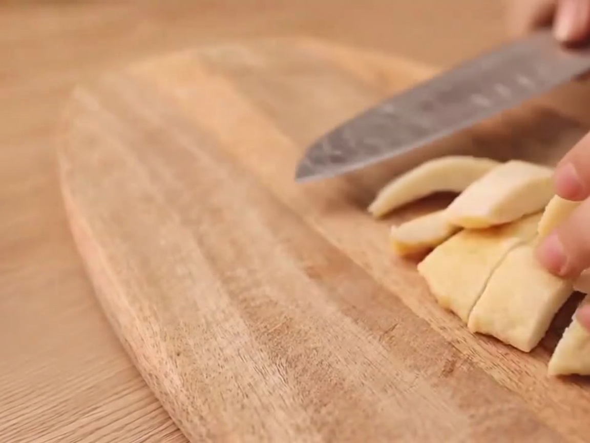 A close-up of a knife making an I shaped cut on a vegetarian sausage.