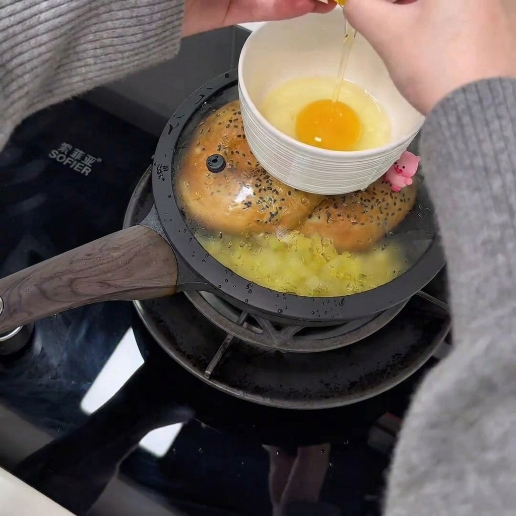 Two raw eggs inside a small white bowl, positioned on the lid of a pan.