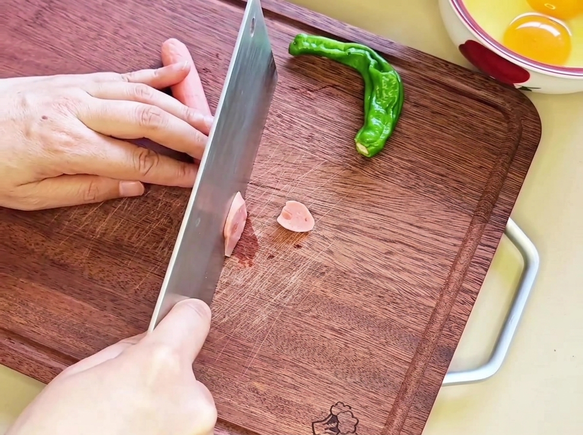 Diagonal slices of sausage arranged neatly on a wooden cutting board, ready for the next step.