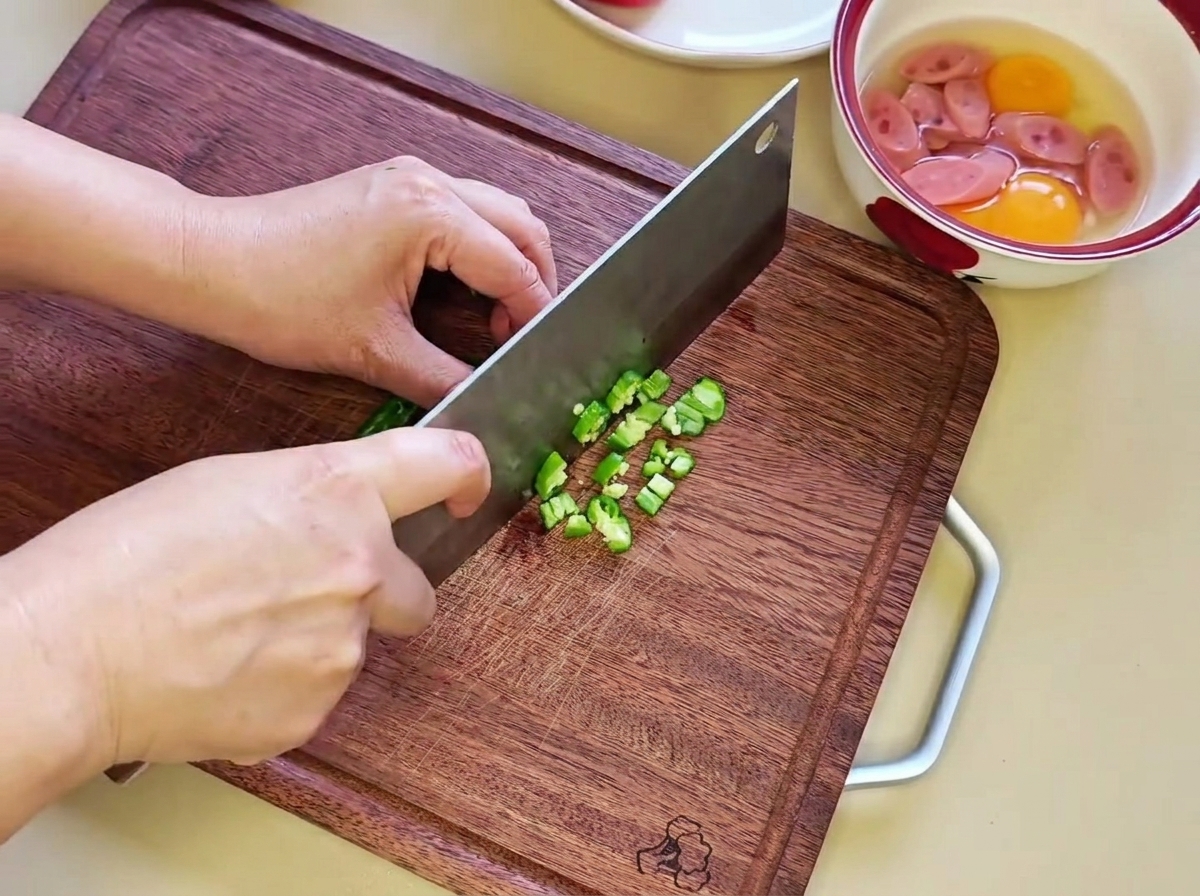 Finely diced green chili pepper pieces resting on a wooden cutting board.