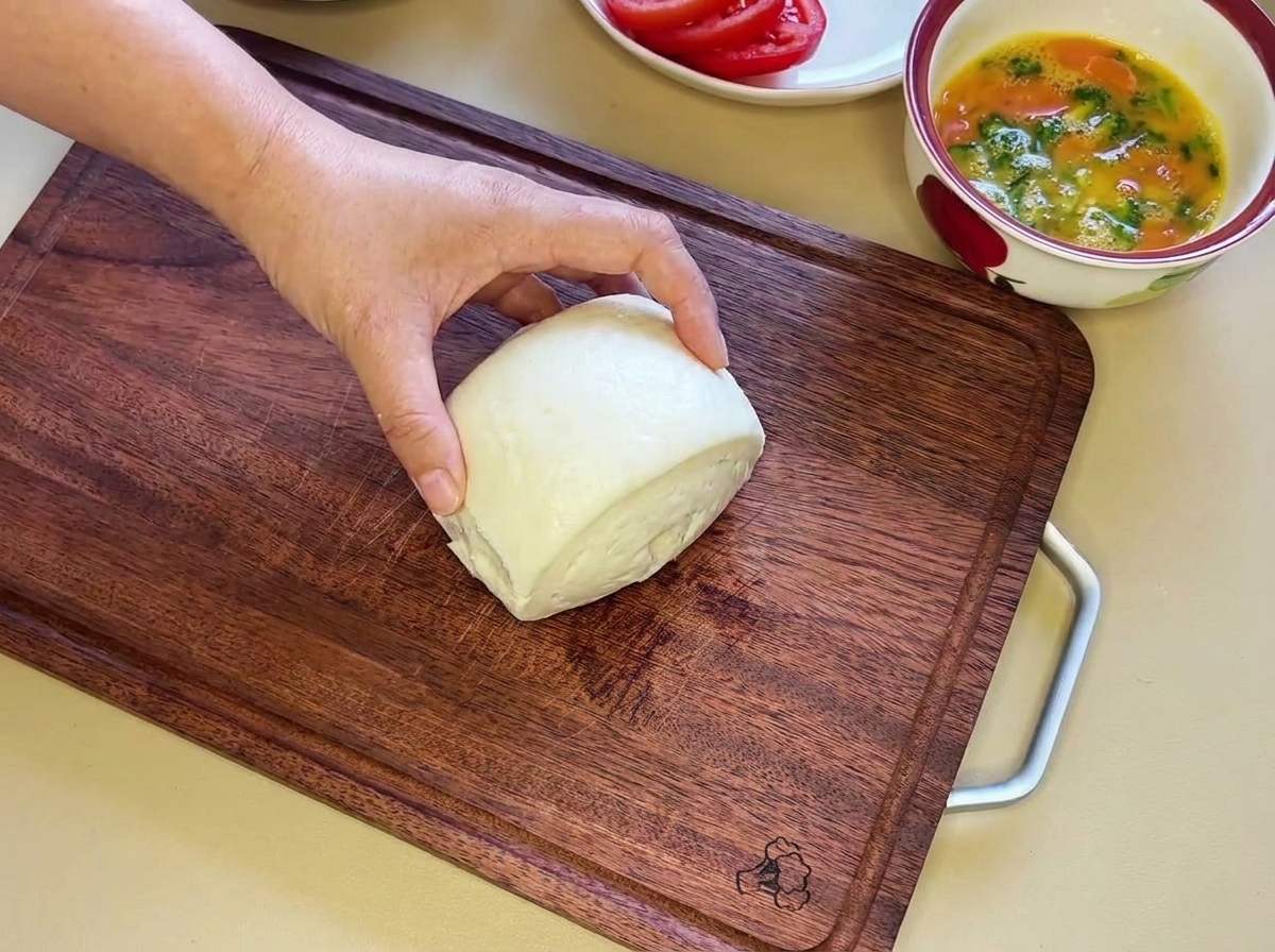 A soft white steamed bun being cut horizontally into two equal halves.