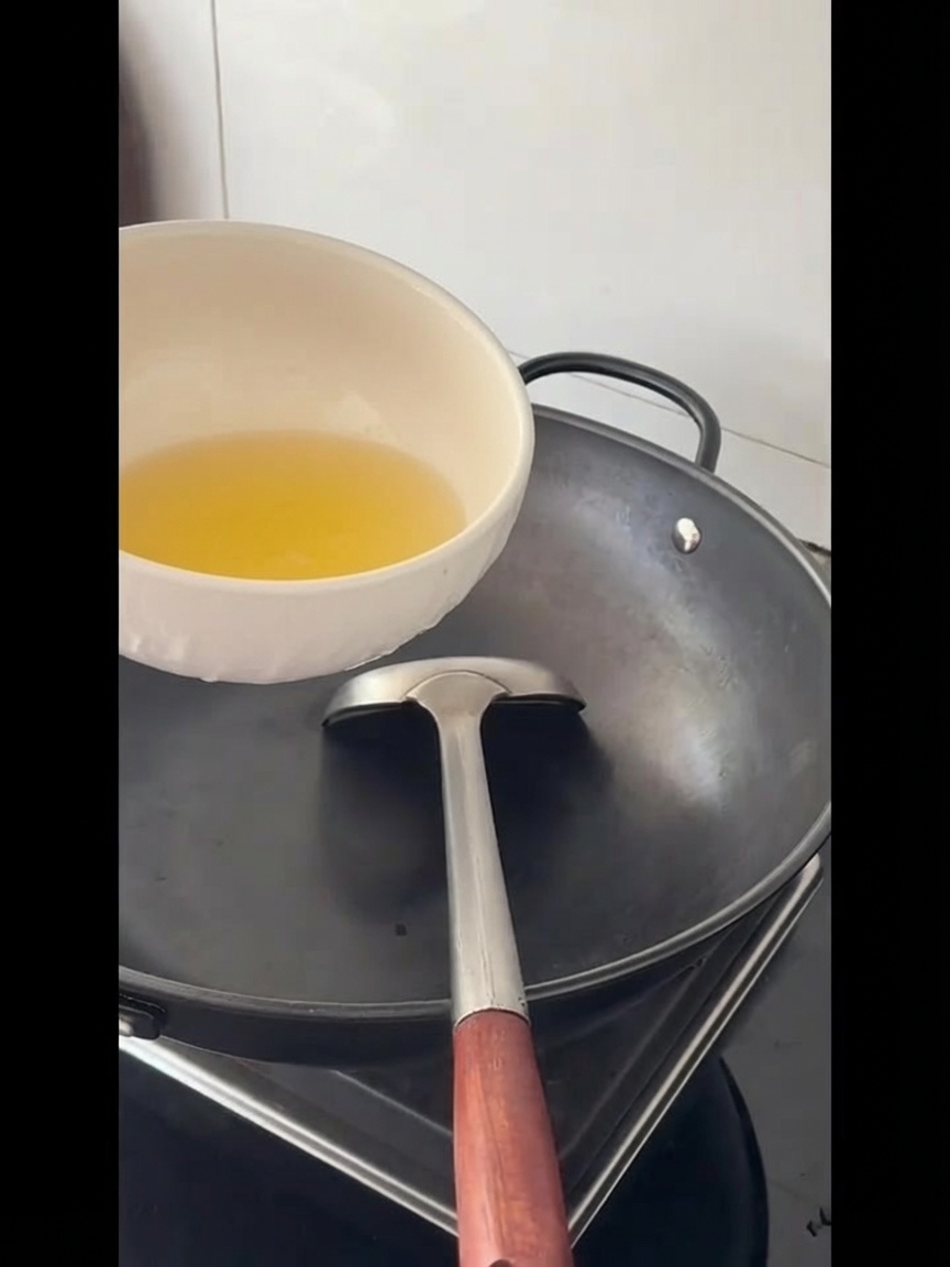 Cooking oil being poured into a large empty wok.