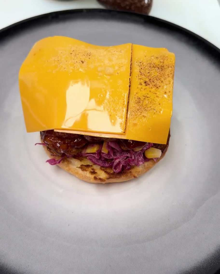 A slice of cheddar cheese melting over the glazed fried chicken, with visible browning from the torch.