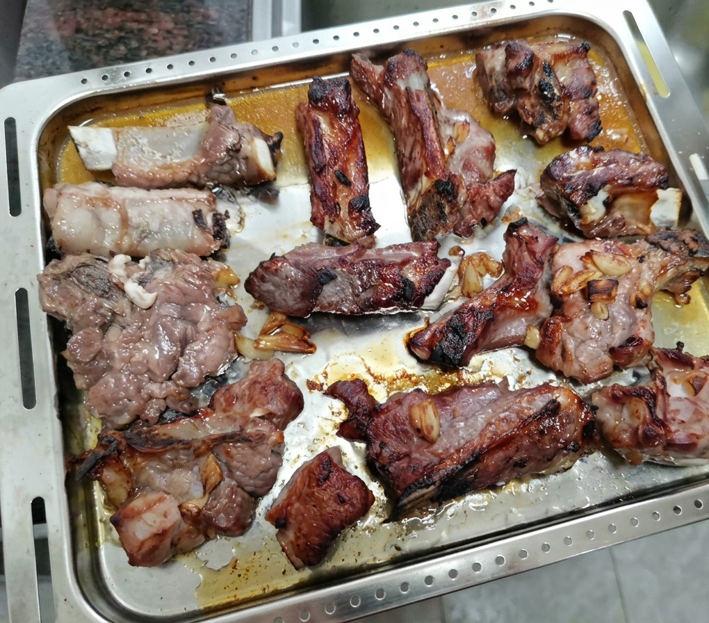 Partially roasted pork ribs resting on a tray, ready to be brushed with honey.