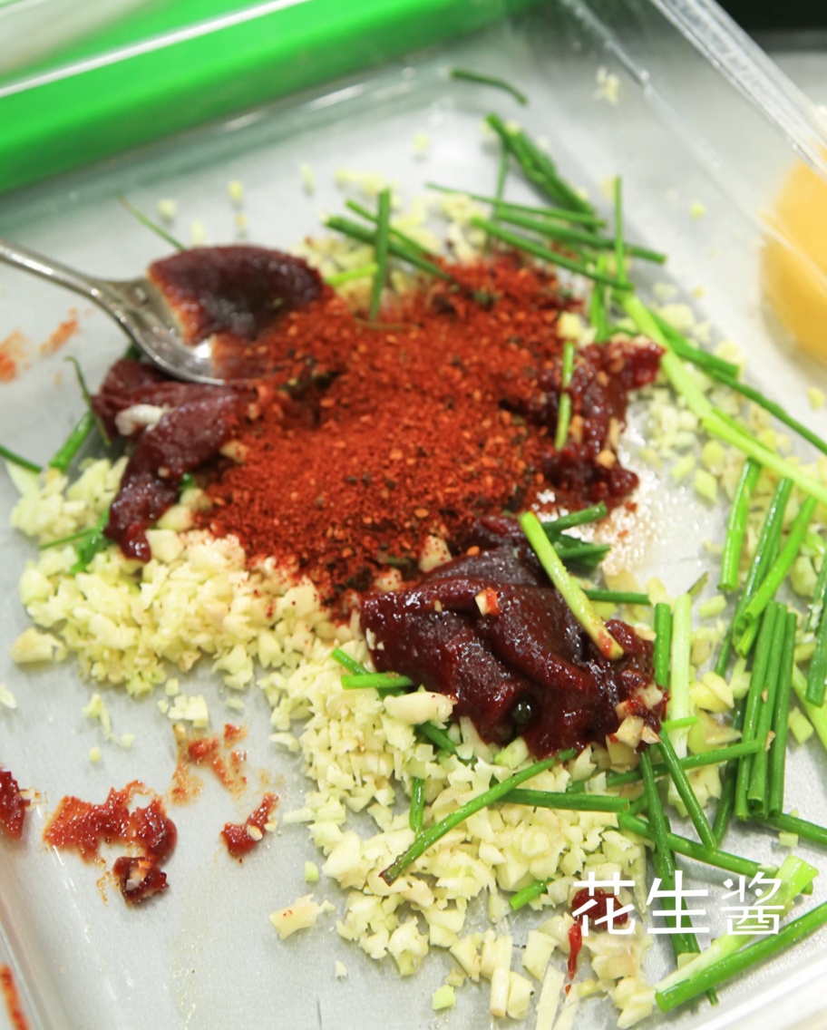 A stream of light soy sauce being poured into the marinade mixture in a container.