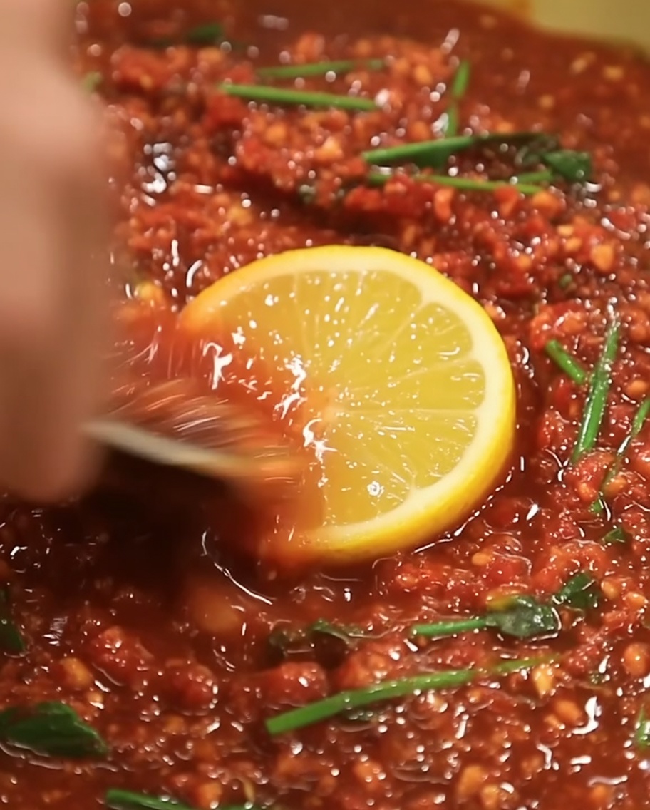 A small amount of golden sesame oil being poured into the center of the dark red marinade mixture.