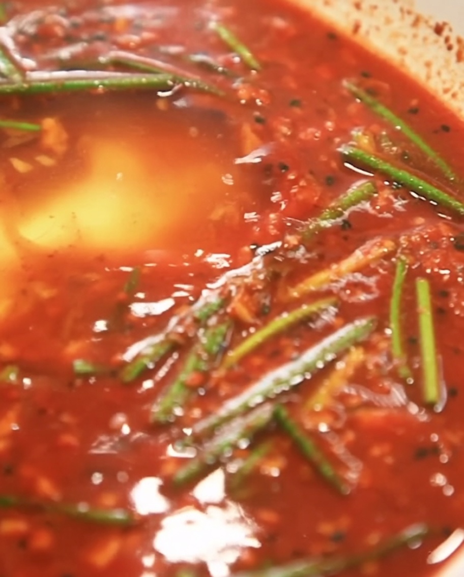 White starch powder being sprinkled into the red marinade base.