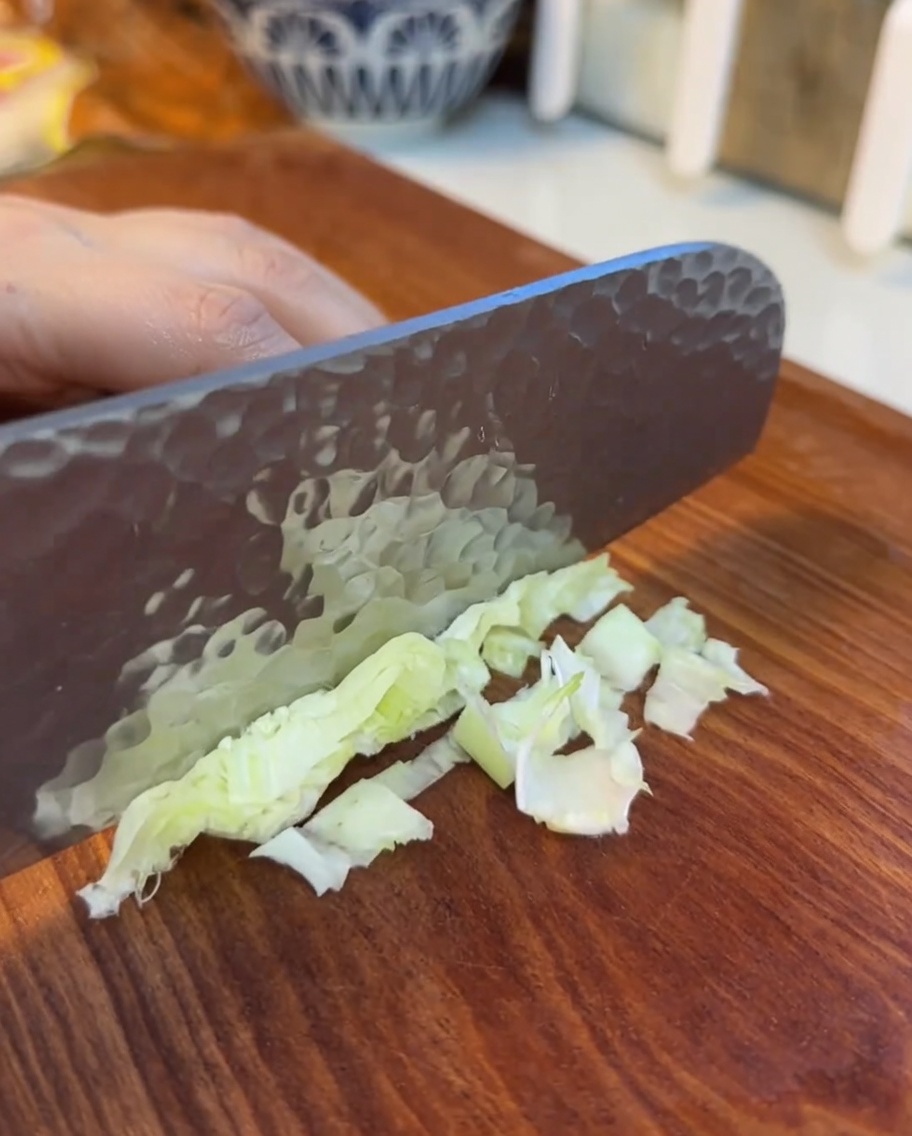 Finely shredded lettuce leaves spread out on a wooden cutting board.