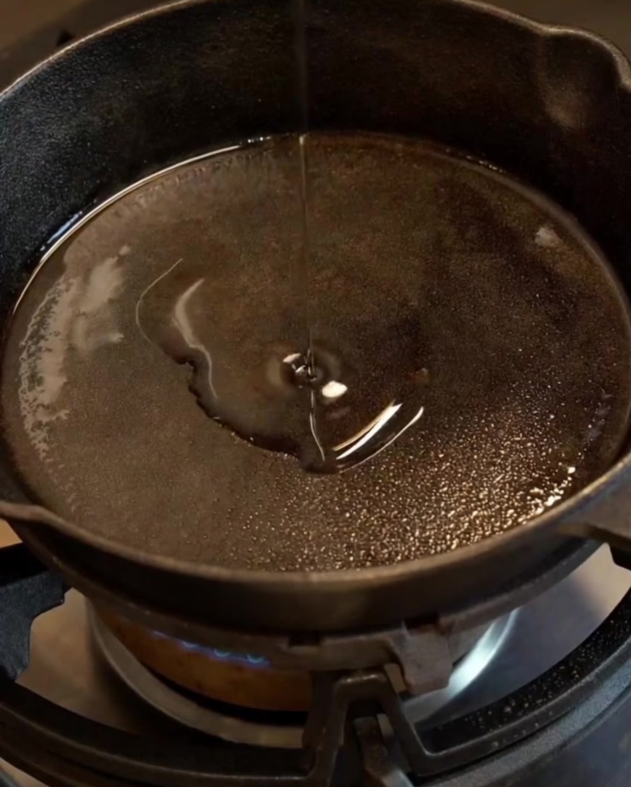 Minced onion and garlic translucent and soft, sizzling in a seasoned cast iron skillet with oil.