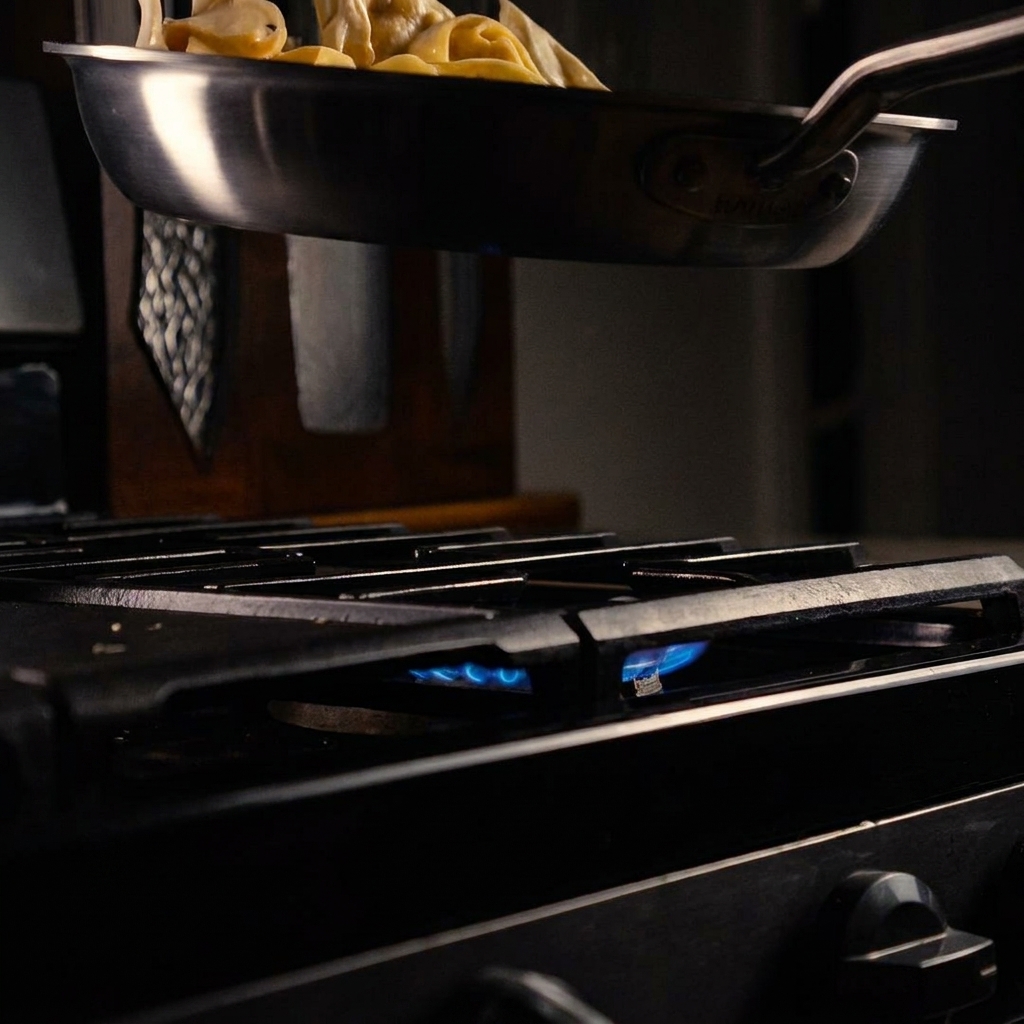 Wide noodles being tossed in a rich, creamy sauce inside a cooking pan.