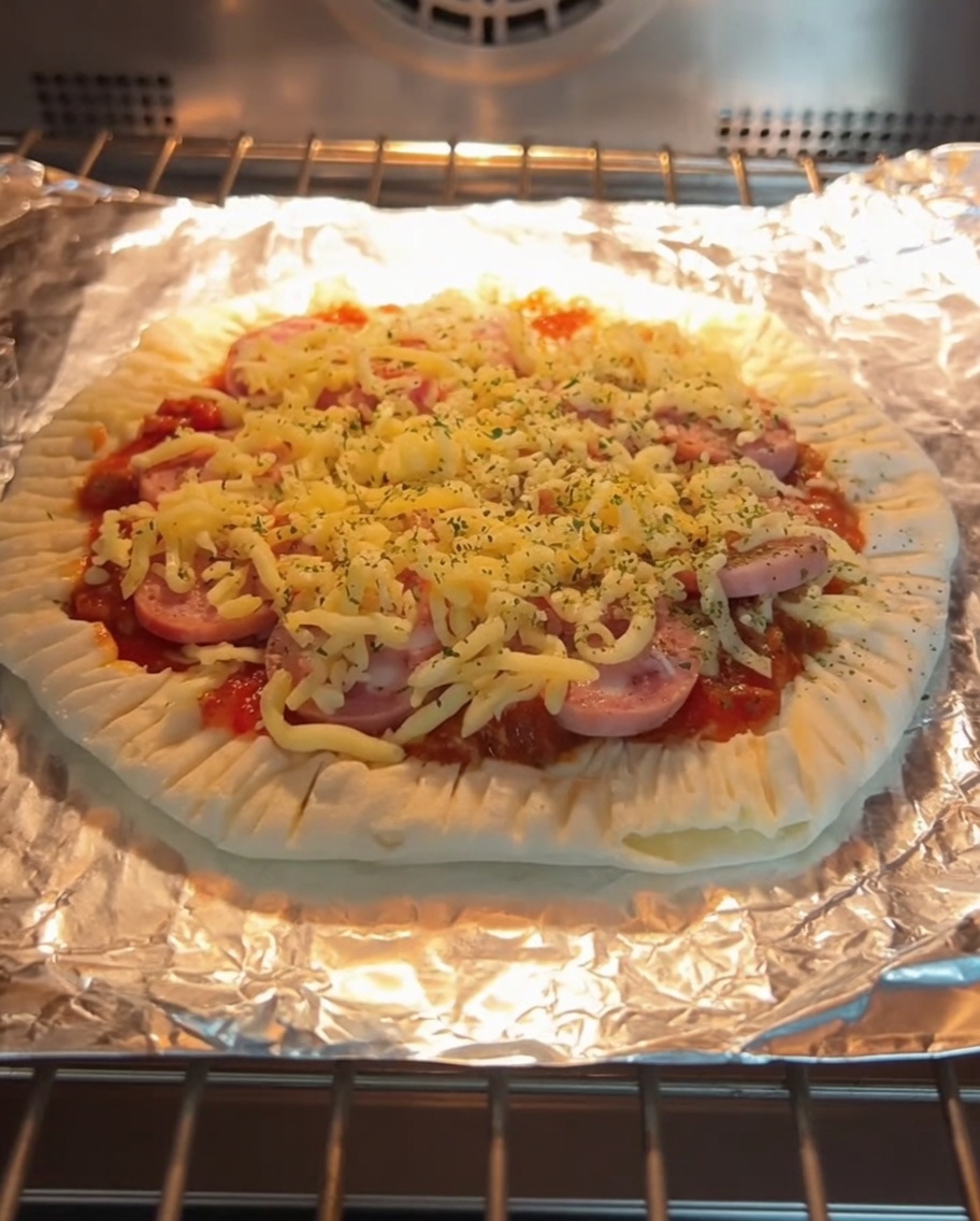 A freshly baked scallion pancake pizza with melted cheese and sausage slices, inside the oven on a baking rack.