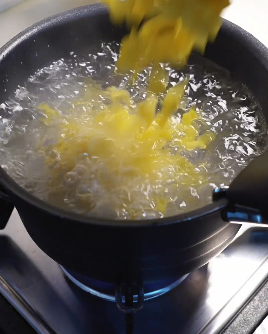 Macaroni boiling in a large pot of water on the stove.