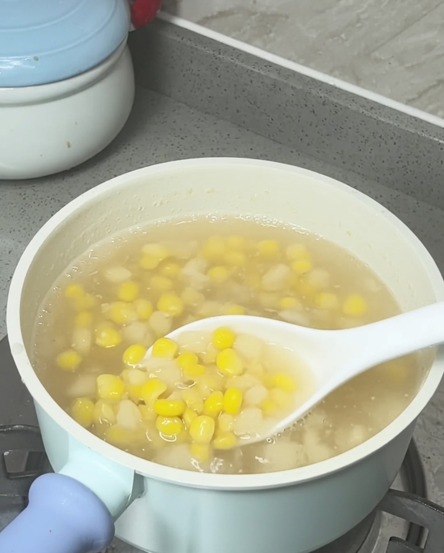 Coconut milk being drizzled into the pot of finished corn and water chestnut soup.