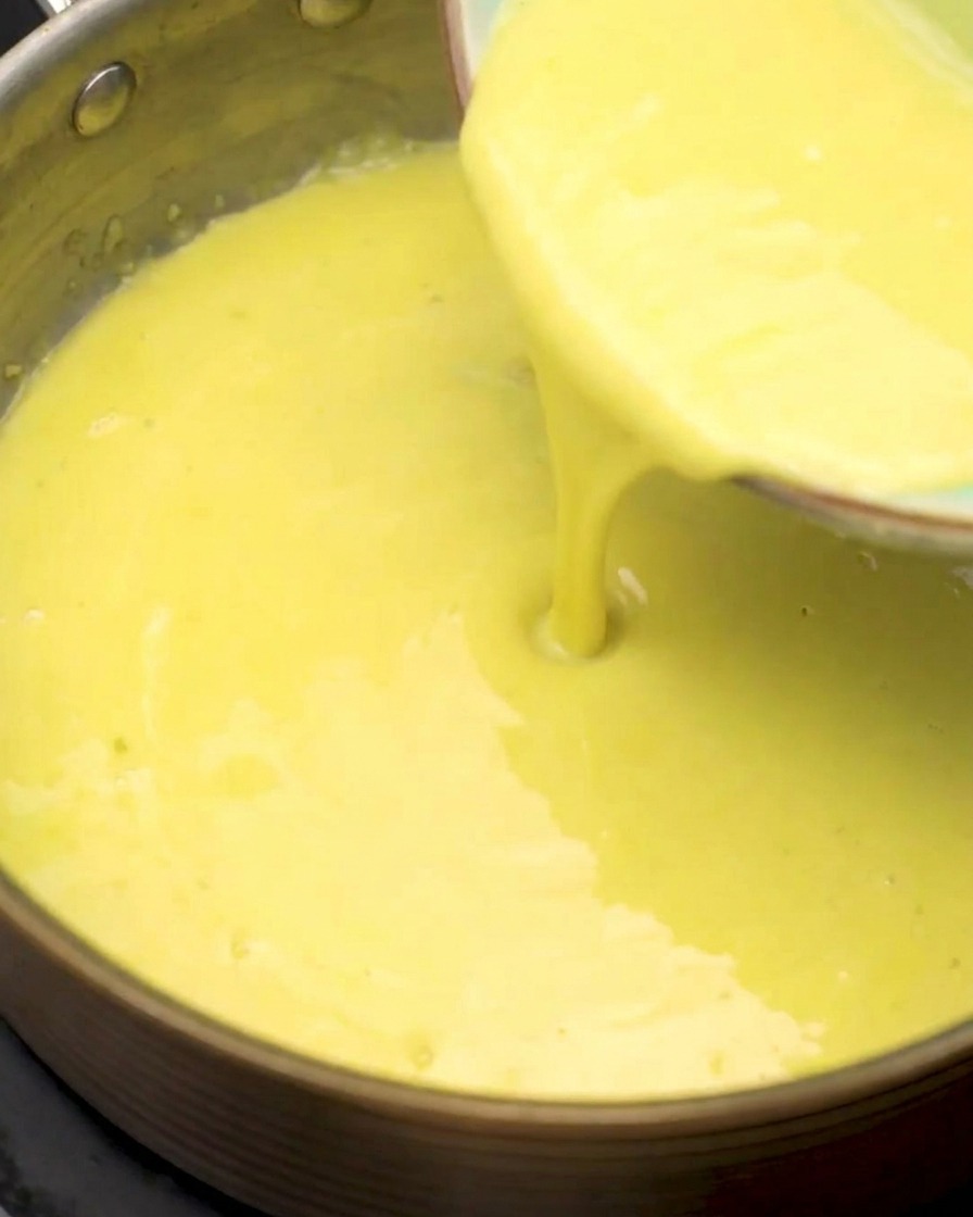 Strained corn juice being poured into the saucepan with the flour and garlic base.