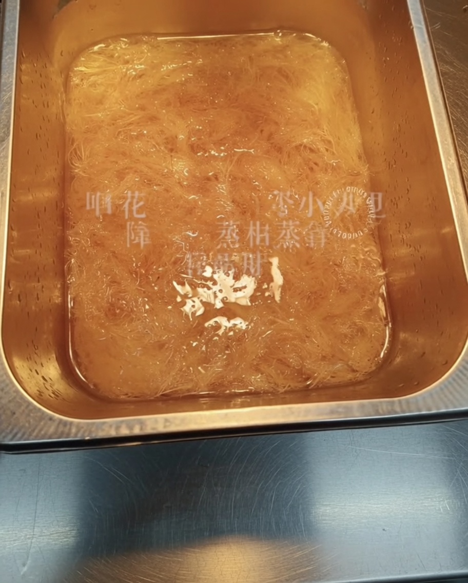 A close-up view of dried, stringy agar-agar soaking in a container of water.