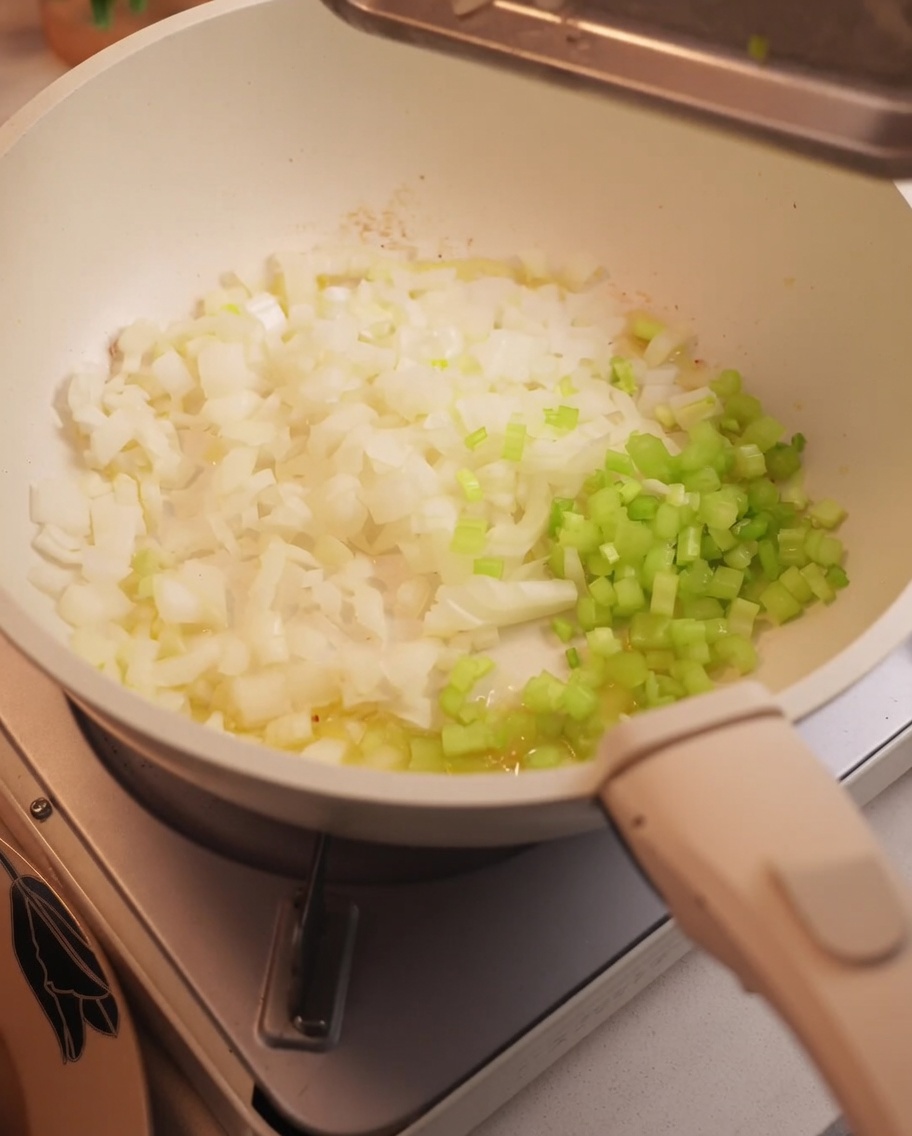 Chopped onions and celery sautéing in a pan.