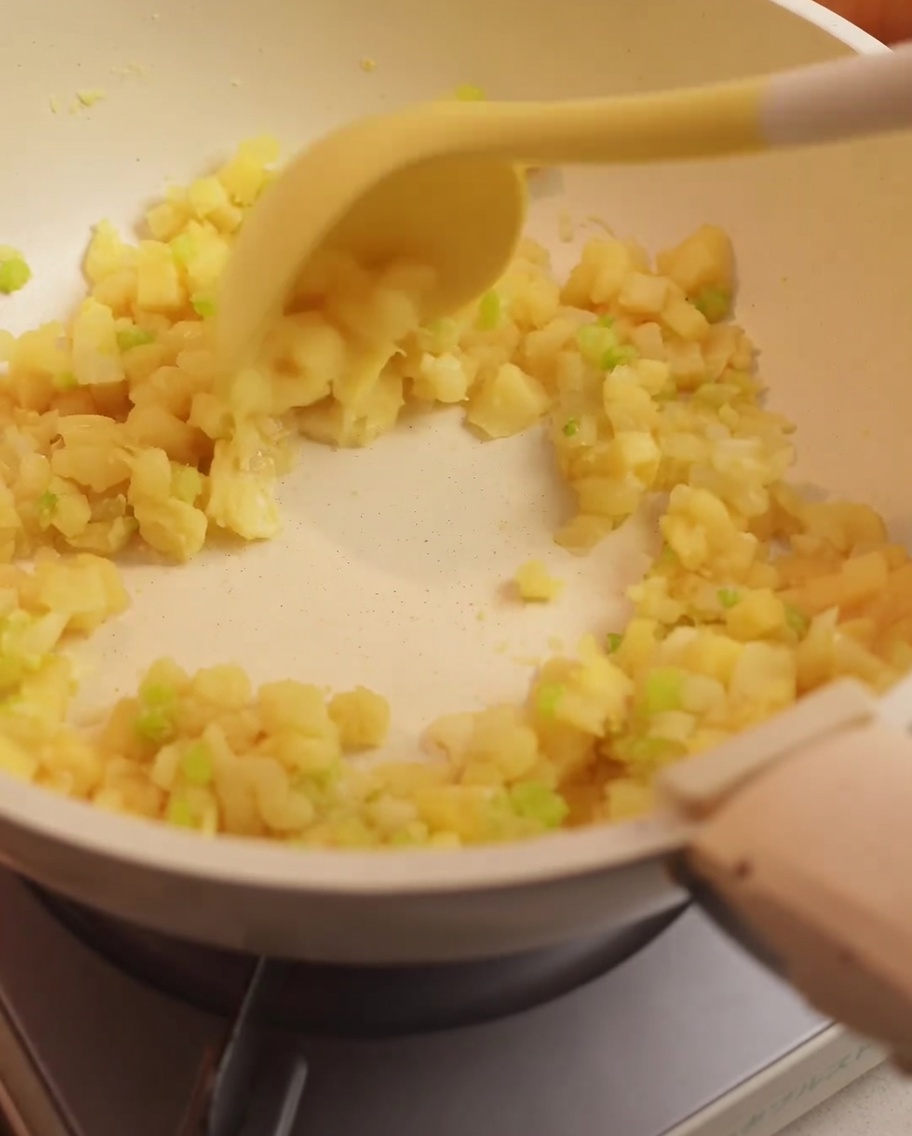 Reserved clam broth being poured into the pan containing sautéed vegetables and flour.