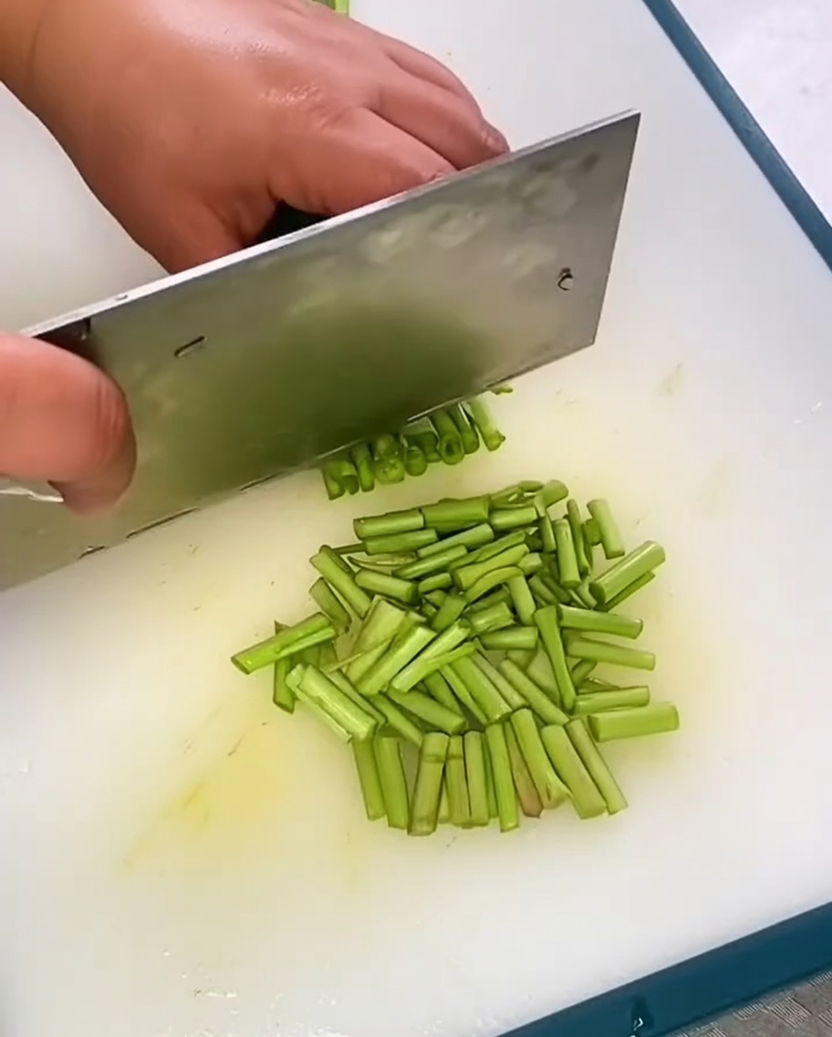 Freshly chopped Chinese chives piled on a clean cutting board.