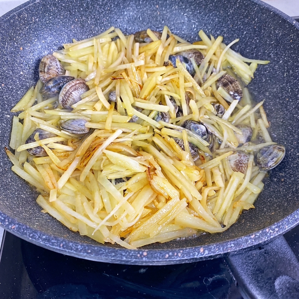 Water being poured into a wok containing stir-fried potato strips and fresh clams.
