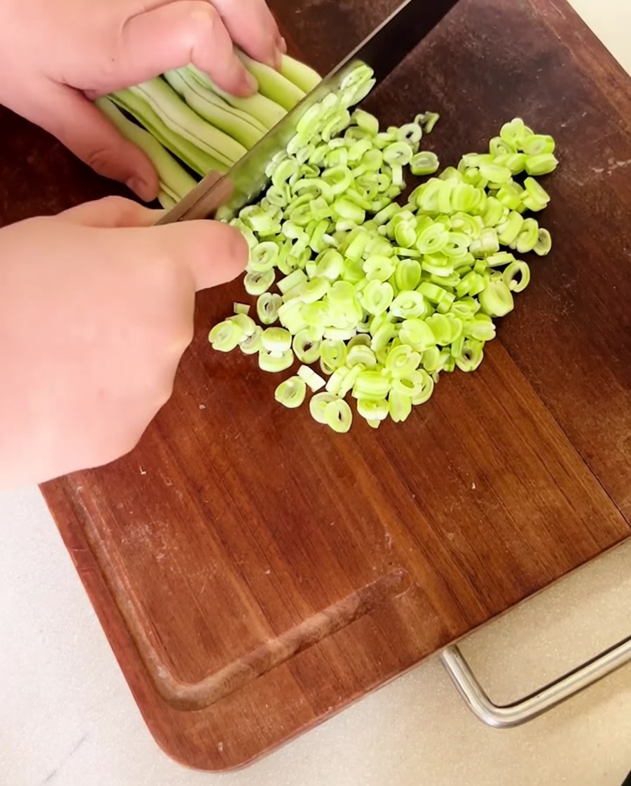 Finely chopped fresh kidney beans spread out on a wooden cutting board.