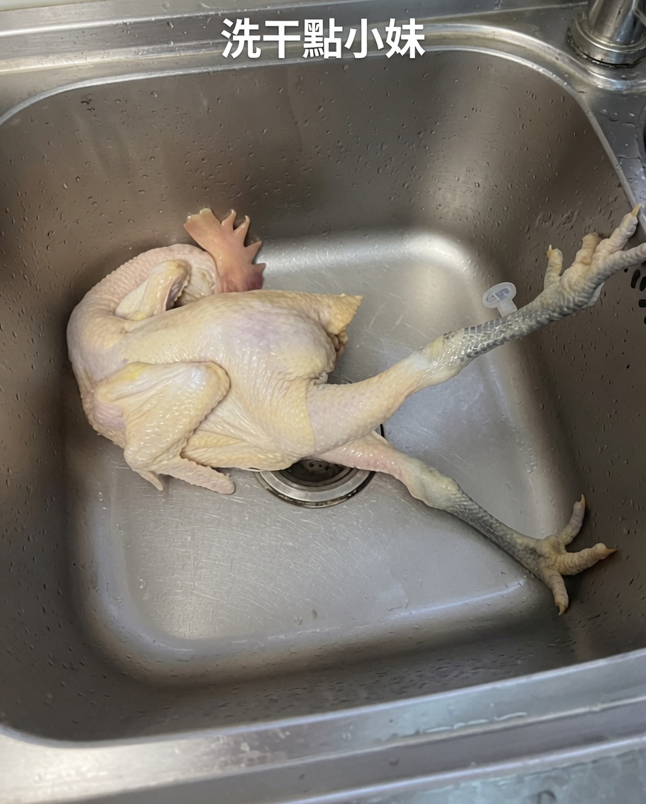 A whole raw chicken being rinsed thoroughly in a stainless steel sink under cold running water.