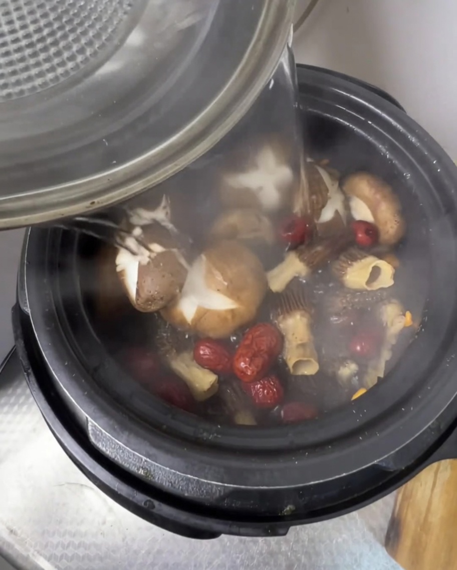 Hot water being poured into the pressure cooker over the ingredients.