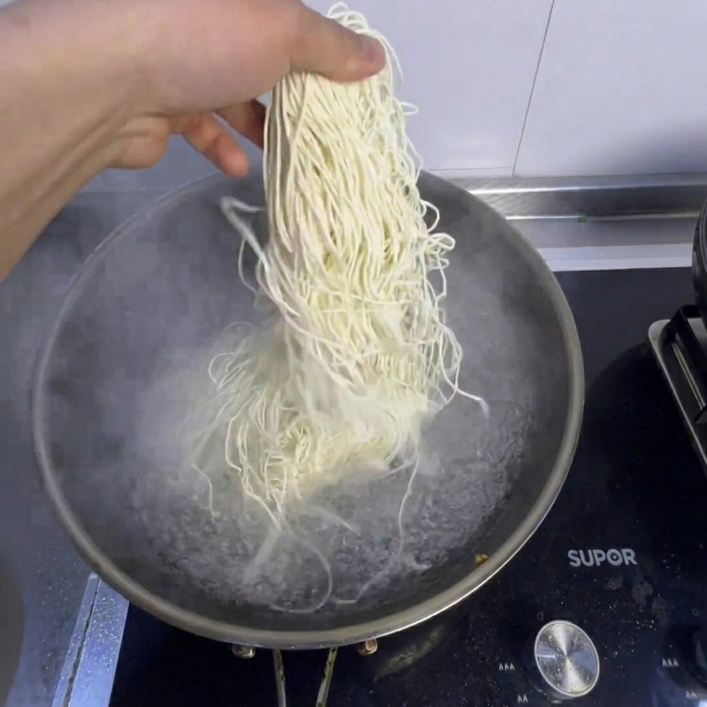 Noodles and fresh bok choy being cooked in a pot of boiling water.