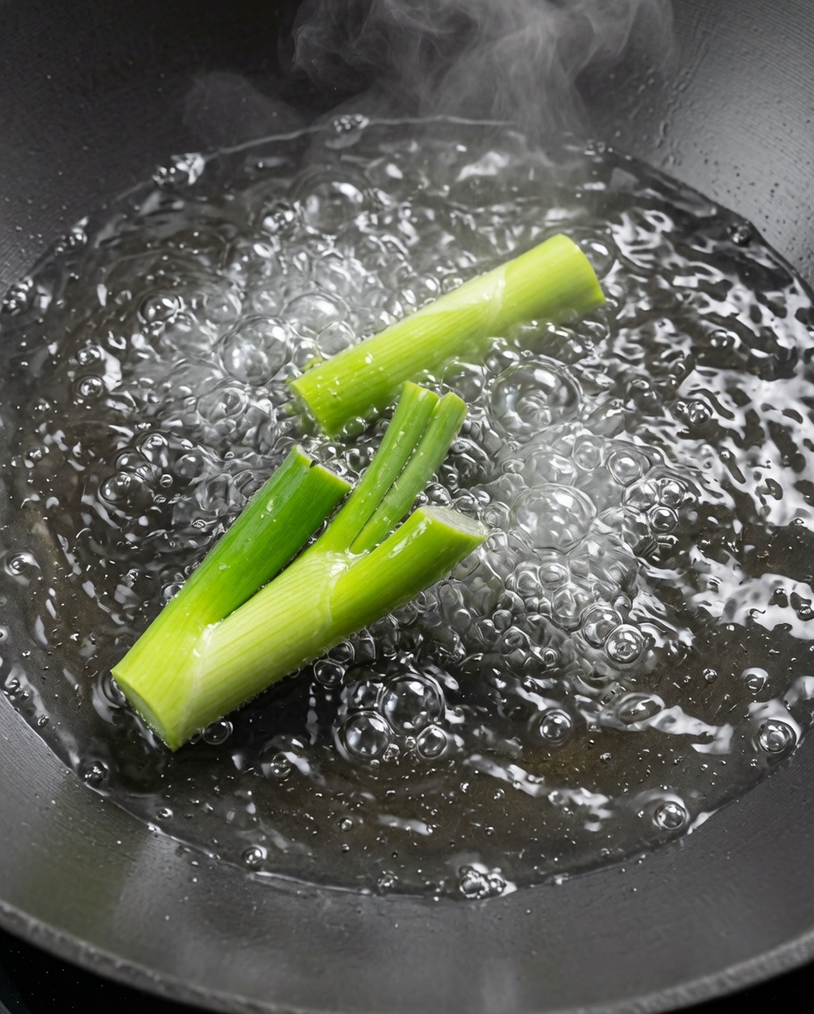 Crawfish being blanched in a large wok of boiling water with scallions.