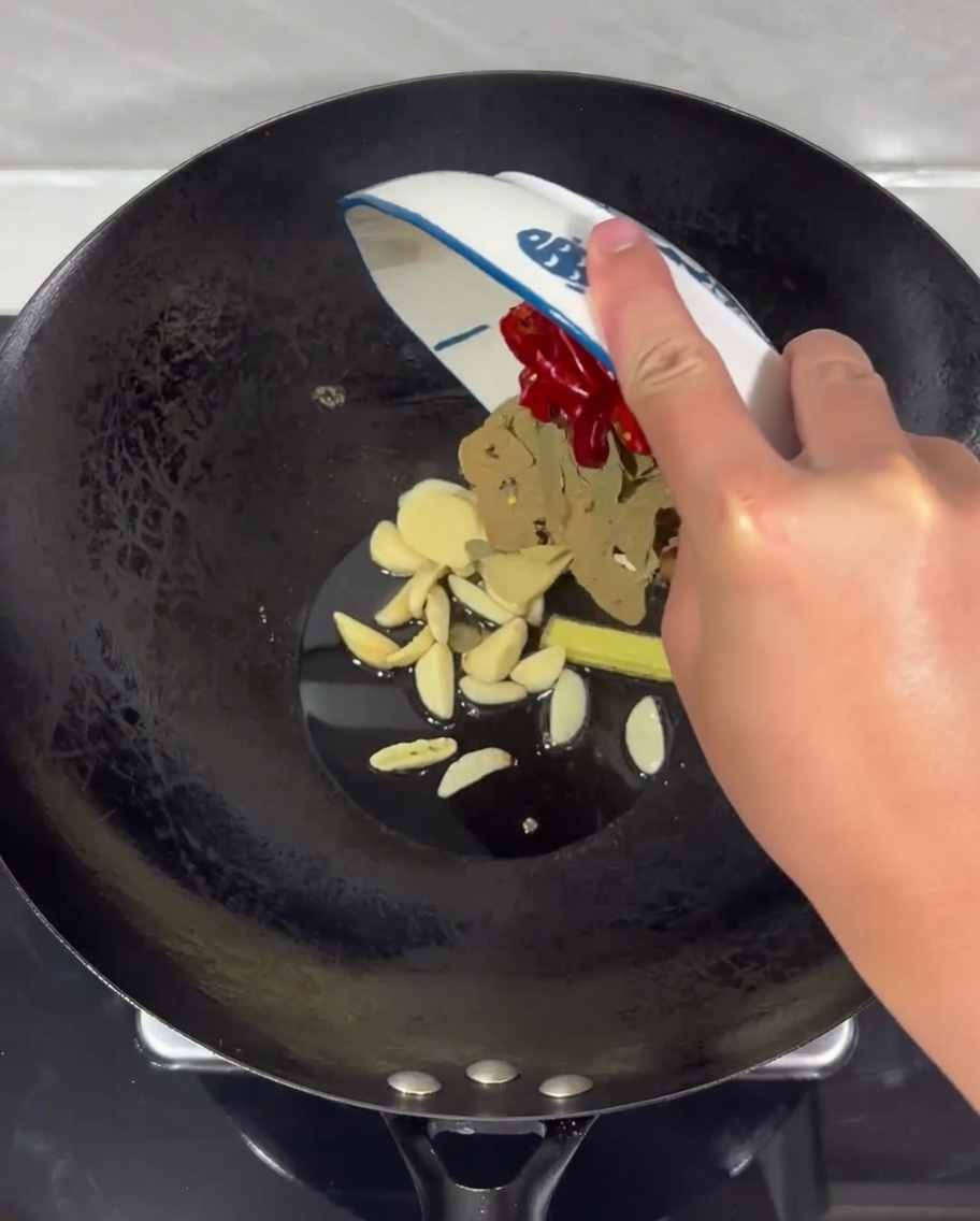 A mix of ginger, garlic, and dried chilies sizzling in hot oil in a wok.