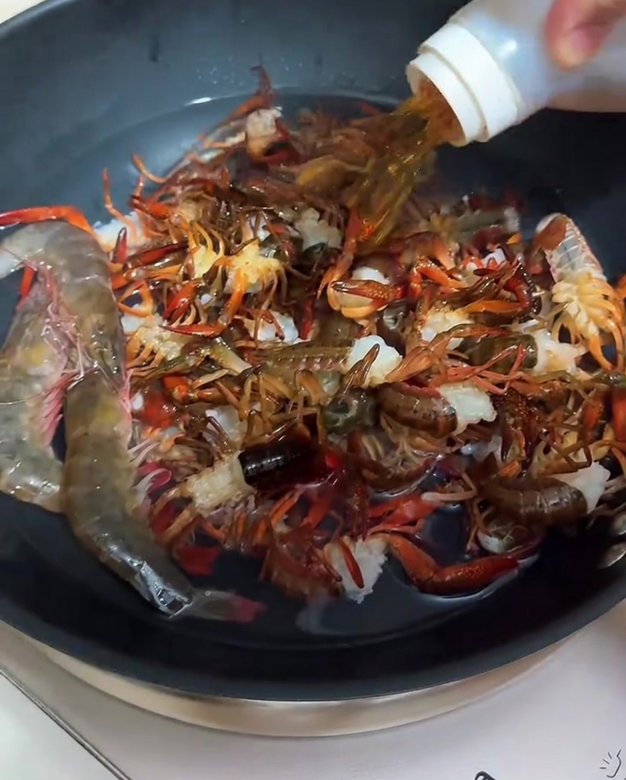 Crayfish being blanched in a pan with water and cooking wine.