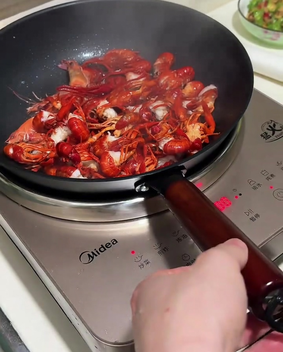 Stir-frying crayfish with aromatics in a pan.
