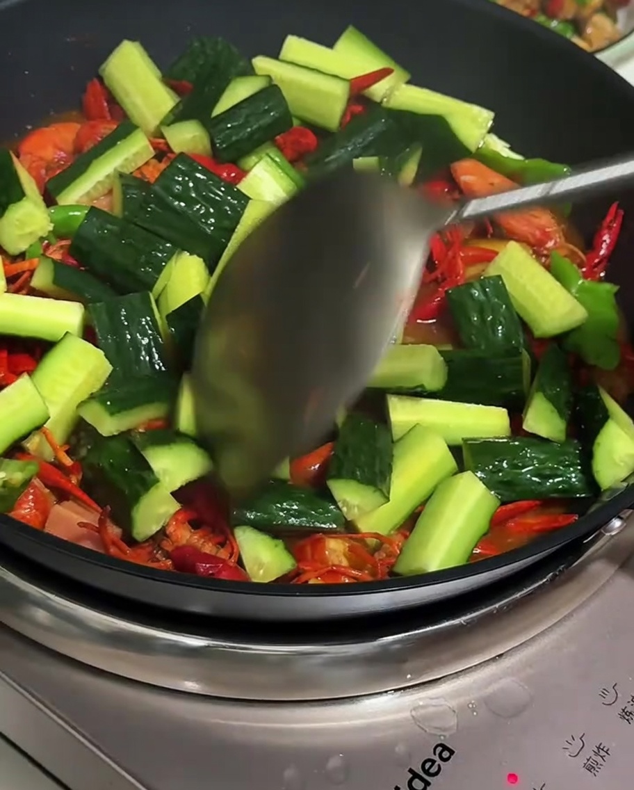 Mixing cucumber slices into the final crayfish dish.